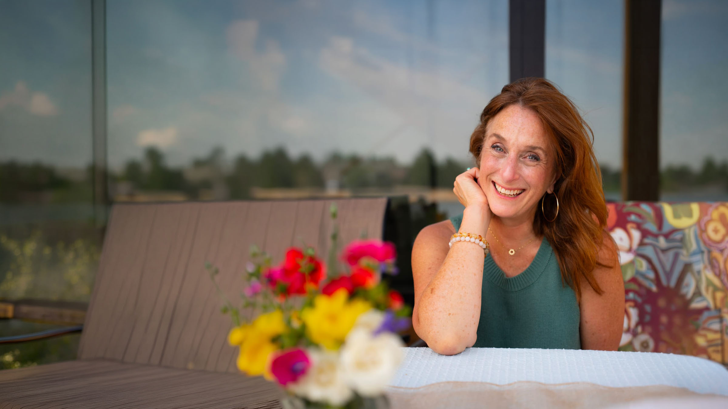 Shaun Harner at a table by a window, chin resting on her hand, listening.
